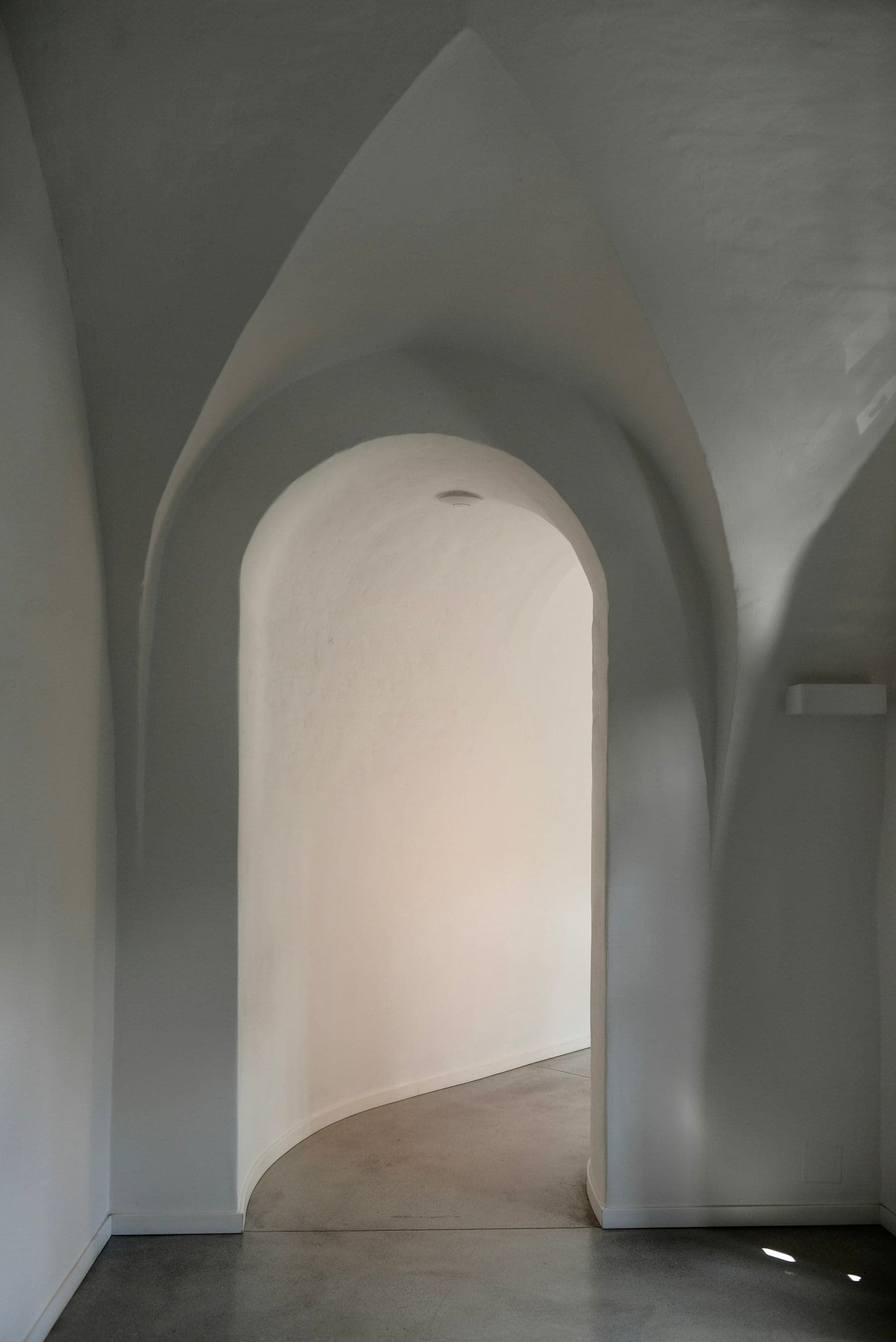 A vaulted plaster passage leading to an arched doorway